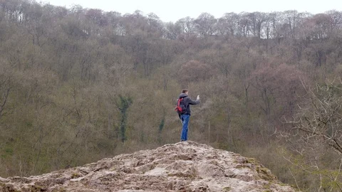 Young man standing on a rock trying to catch a signal on the mobile phone Stock Footage 106777142