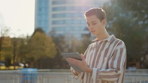 Young Man Standing on the Street Using his Tablet, Texting With Friends Stock Footage 237600429