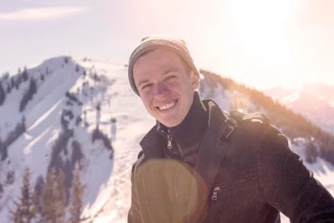 Young man standing in the sun surrounded by snowy mountains Stock Photos