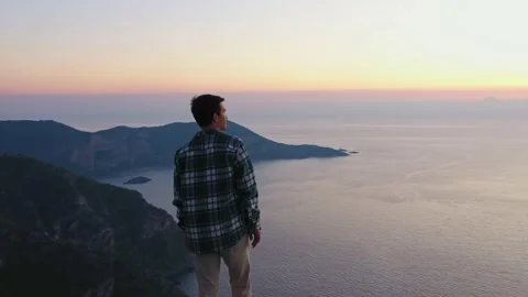 Young man standing on top of the mountain and enjoying scenery sunset 動画素材 258890047