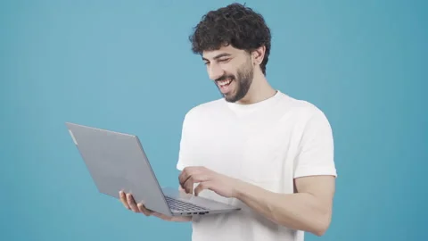 Young man standing using laptop rejoicing, looking at screen. Stock Footage 228855073