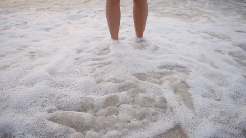 Young man standing on water waves on beach Slim feet and legs on seafront Video stock 96166865