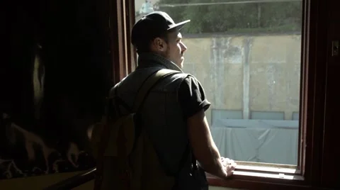 Young man standing at the window and looking dreamily into the street Stock Footage 51757356