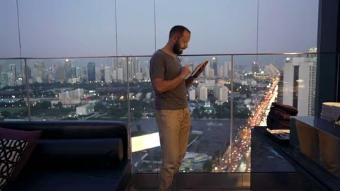 Young man standing  withtablet computer on terrace in the city, 4K Stock Footage 74212885