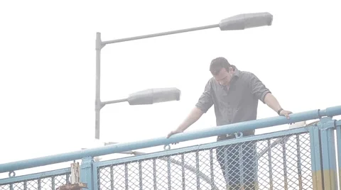 A young man stands on the bridge under the street lights and looks down Stock Footage 49669704