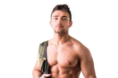A young man stands confidently in a studio, his bare upper body visible as he Stock Photos