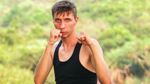 Young man stands facing the camera in a boxer's stance Stock Photos