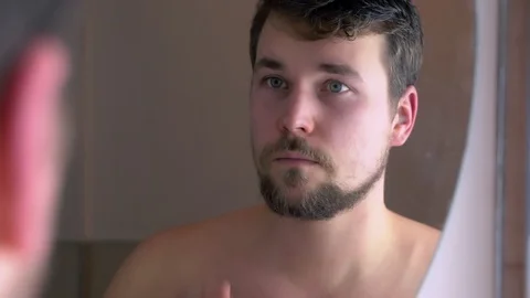 A young man stands in front of a bathroom mirror Stock-Footage 124572084