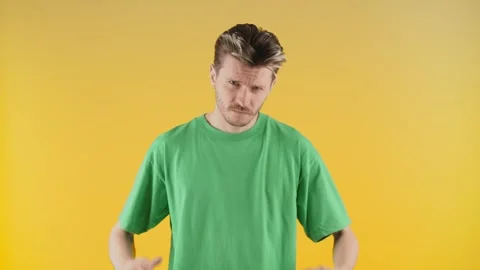 A young man stands in front of the camera and shows a gesture of aggression. A Stock Footage 241135295