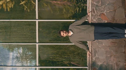 A Young Man Stands In Front Of Large Window Of Botanical Garden 4K Video Stock Footage 274758544