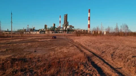 A young man stands at his car in the background of an oil refinery Stock Footage 133283053