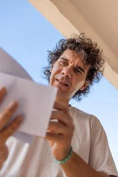 A young man stands at a mailbox with envelopes and reads a letter. Mail rec.. Stock Photos