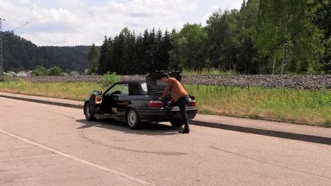A young man stands near a broken car. 库存影片 113459809