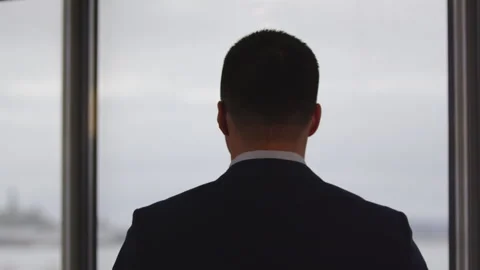 Young man stands in official suit near office window Stock Footage 246472051