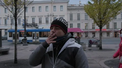 Young man stands sad and smokes a cigarette in the city center Stock Footage 145322916