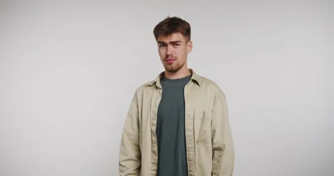 Young man stands with a thoughtful expression in a simple studio setting Vídeo Stock 326788385
