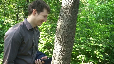 Young man stands in the woods, thinks about something and works on the phone Stock Footage 77150188
