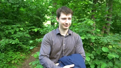 A young man stands in the woods,throws the jacket over his shoulder Video stock 77127560