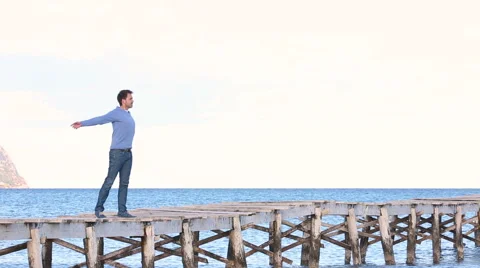 Young man staying on the jetty opening his arms Stock Footage 57764315