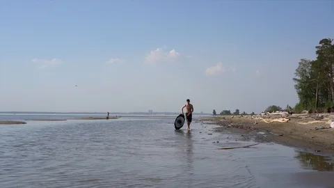 A young man steps along the shore with a board for a skimboard Video stock 90805847