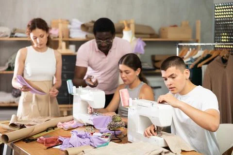 Young man stitching at machine during sewing class for adults Foto stock