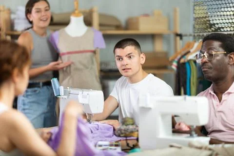 Young man stitching at machine during sewing class for adults Stock Photos