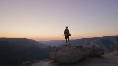 Young man on a stone high in the mountains after sunset, Yosemite, Half Dome Stock Footage 270990578