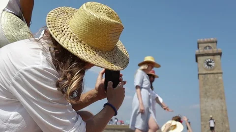Young man in a straw hat taking a picture of a group of girls with a smartphone. Stock Footage 106648388