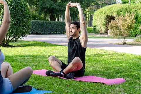 Young man stretching arms practicing outdoor yoga Stock Photos