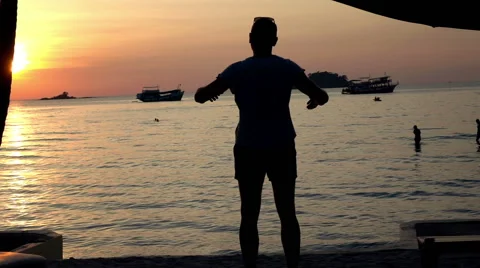 Young man stretching his arms during sunset on beach, slow motion shot at 240fps Видео 59125528