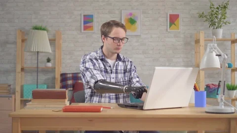 Young man student with bionic prosthetic hand working at a laptop Stock Footage 119568469