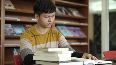 Young man student in library desk reading and yawning tired In the afternoon  Stock Footage 122586186