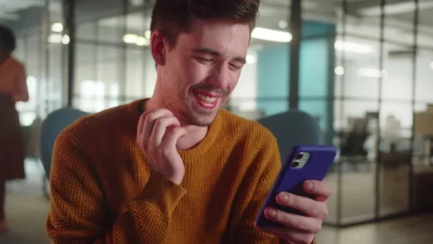 A young man-student sits on the chair and reads humorous posts on the Internet Stock Footage 175469841