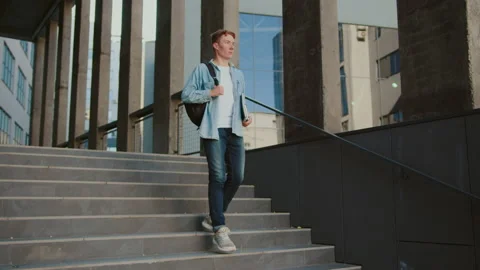 Young man student walking down the stairs near university or office building Stock Footage 142049350