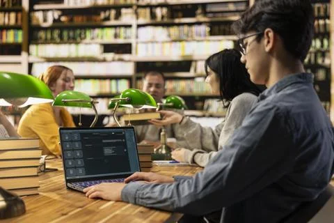 Young man student working with AI chatbot software during library group study Stock Photos
