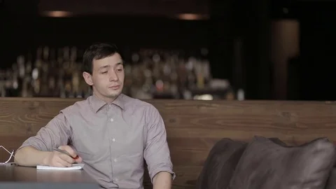 Young man student writing in notepad in cafe Stock Footage 69886943