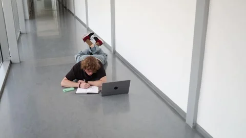 Young man studies with laptop on floor Stock Footage 338277356