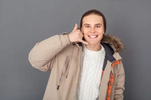 Young man studio isolated on grey winter style looking camera showing call Stock Photos