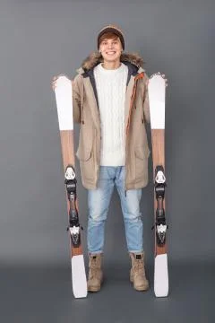 Young man studio isolated on grey winter style holding skis joyful full-body Stock Photos