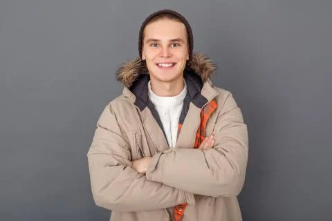 Young man studio isolated on grey winter style looking camera crossed arms Foto stock