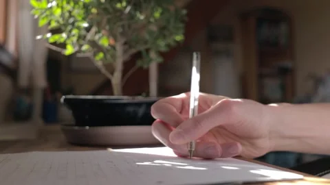 Young man studying and writing. Hand writing with a bonsai tree behind Stock Footage 177867451