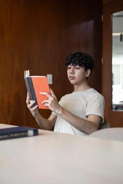 Young man, studying from the front, immersed in a book. Foto stock