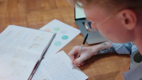 Young man studying at home writes in his notes and reads a textbook Stock-Footage 164371735