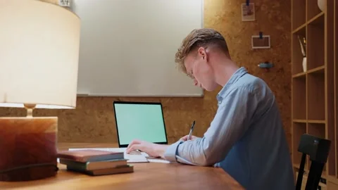 Young man studying at home writes in a notebook and reads a textbook 스톡 동영상 164374851