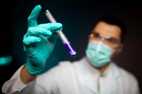 Young man studying liquid sample contained in a test-tube Stock Photos