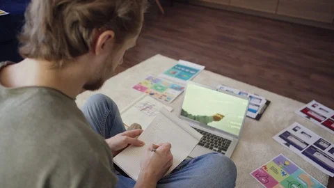 Young man studying online sitting on floor at home Stock Footage 128569147