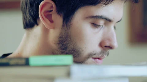 Young man studying on a stack of books Stock Footage 32355142