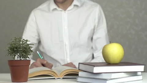 Young Man Studying with Stack of Books and Apple as Symbol of Knowledge Stock Footage 154659323
