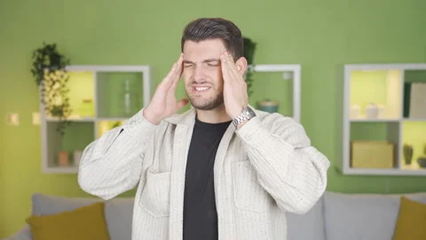 The young man suddenly has a headache and is rubbing his head in pain. Stock Footage 232221331