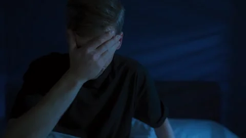 Young man suddenly wakes up in the middle of the night, struggling with insomnia 스톡 동영상 322780839